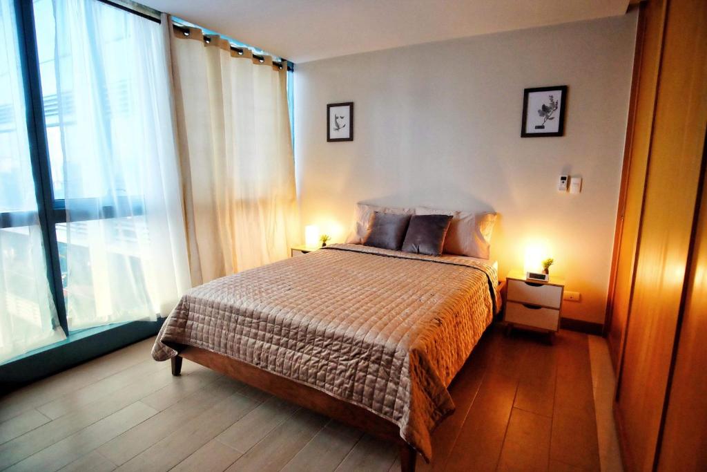 um quarto com uma cama e uma grande janela em One Uptown Residences in Uptown BGC em Manila