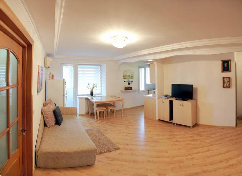 een woonkamer met een bank en een tafel en een keuken bij Студия на Соборной in Nikolayev