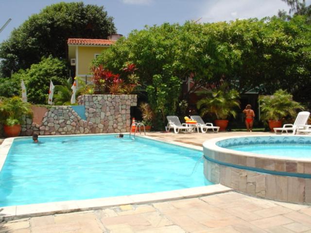 une grande piscine bleue avec des chaises et une table dans l'établissement Chalés Recanto dos Golfinhos, à Ponta do Funil