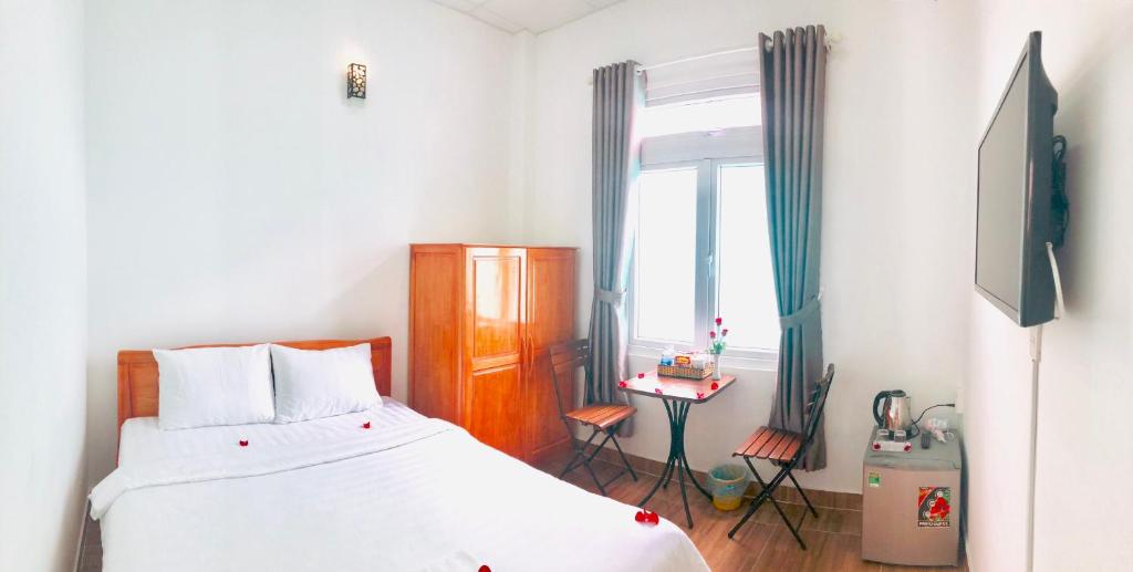 - une chambre avec un lit, une télévision et une fenêtre dans l'établissement Trinh Nguyen Homestay, à Đà Lạt