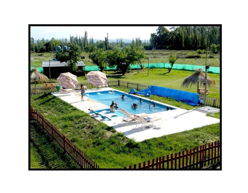 une grande piscine avec des personnes dans une cour dans l'établissement Cabañas Haras de Cuyo, à San Rafael