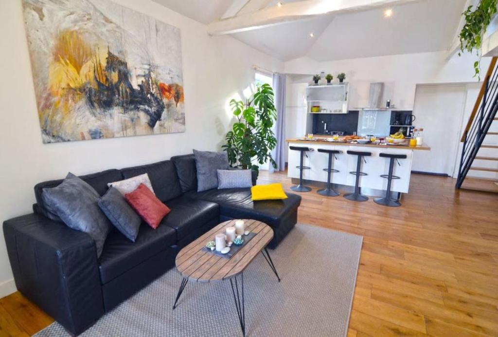 ein Wohnzimmer mit einem schwarzen Sofa und einem Tisch in der Unterkunft Duplex Elegant & Moderne - 3 chambres - Rooftop terrasse & Jacuzzi- Chélitz in Biarritz