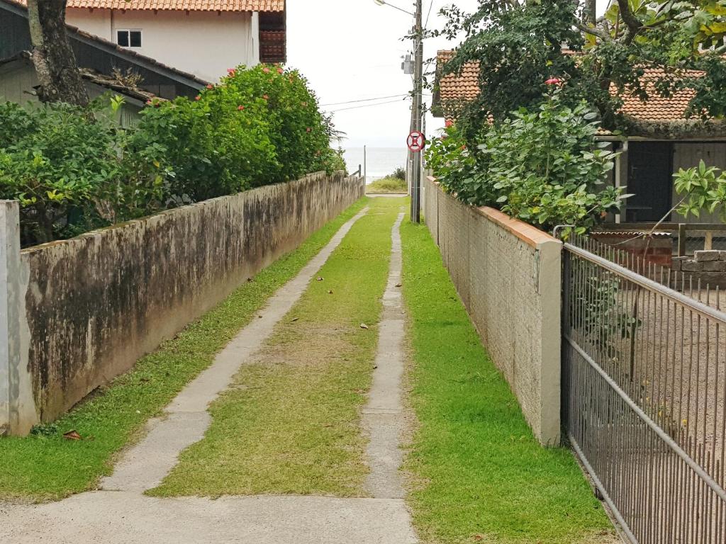 une allée vide avec clôture et pelouse dans l'établissement Casa 3 quartos Bombinhas lado Mar ou AP de 2 quartos, à Bombinhas