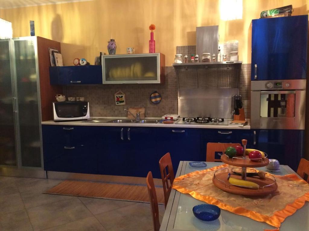 a kitchen with blue cabinets and a table with a bowl of fruit at la casa di laura in Calascibetta