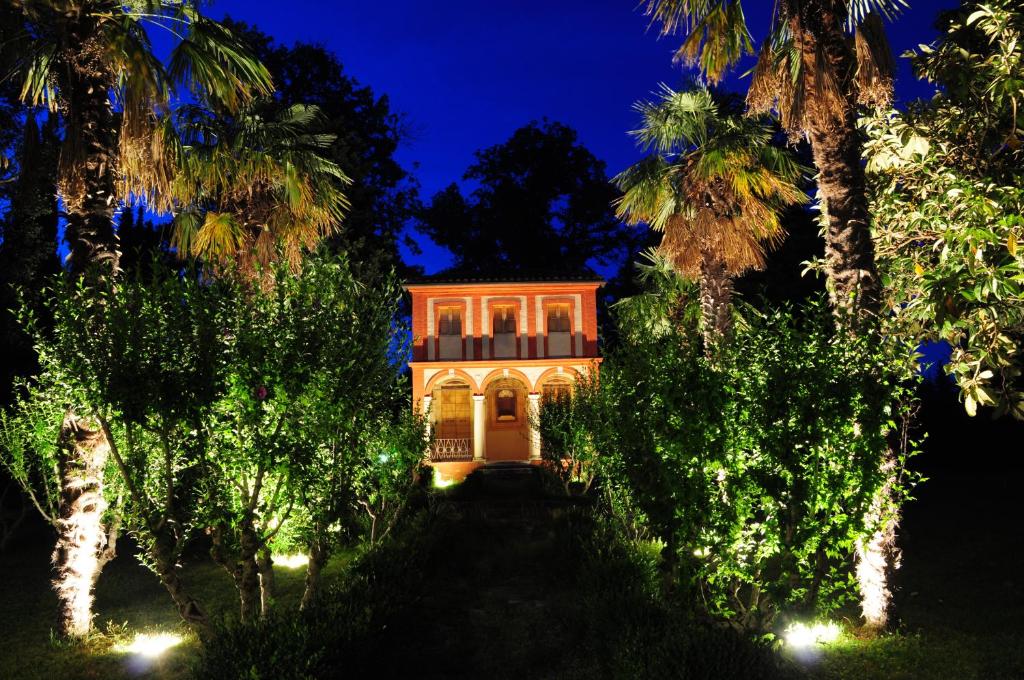 a house in the middle of a forest of palm trees at night at Il Roccolo Di Valcerasa in Treia