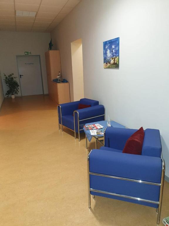 a waiting room with blue chairs and a table at Hanse Haus Pension in Greifswald