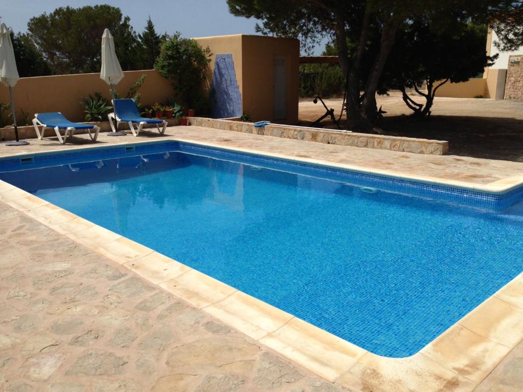 a large swimming pool with blue water in a yard at Casa Victor in Playa Migjorn