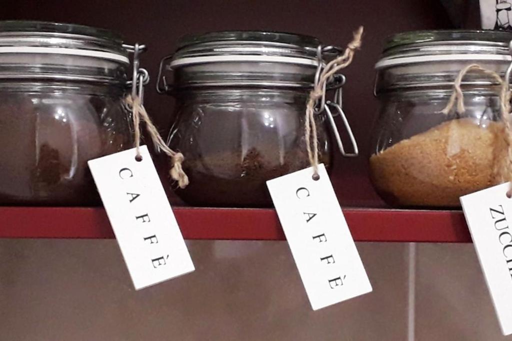 three jars of food on a red shelf with tags at Apartment TRio in Novi Sad