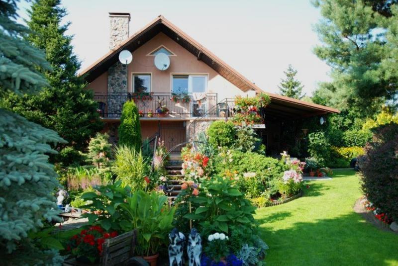 une maison avec un bouquet de fleurs dans la cour dans l'établissement Agroturystyka Maria i Jan Bryjka, à Mikorowo