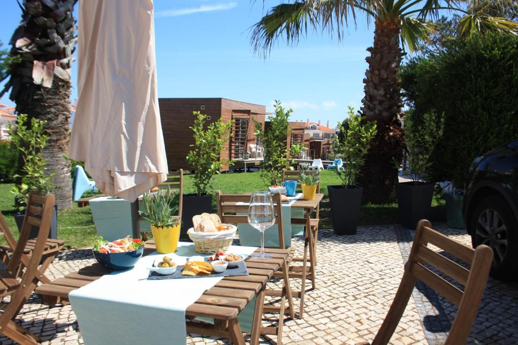 a table and chairs with food and wine on a patio at Golden Halcyon - Ericeira Villas in Ericeira