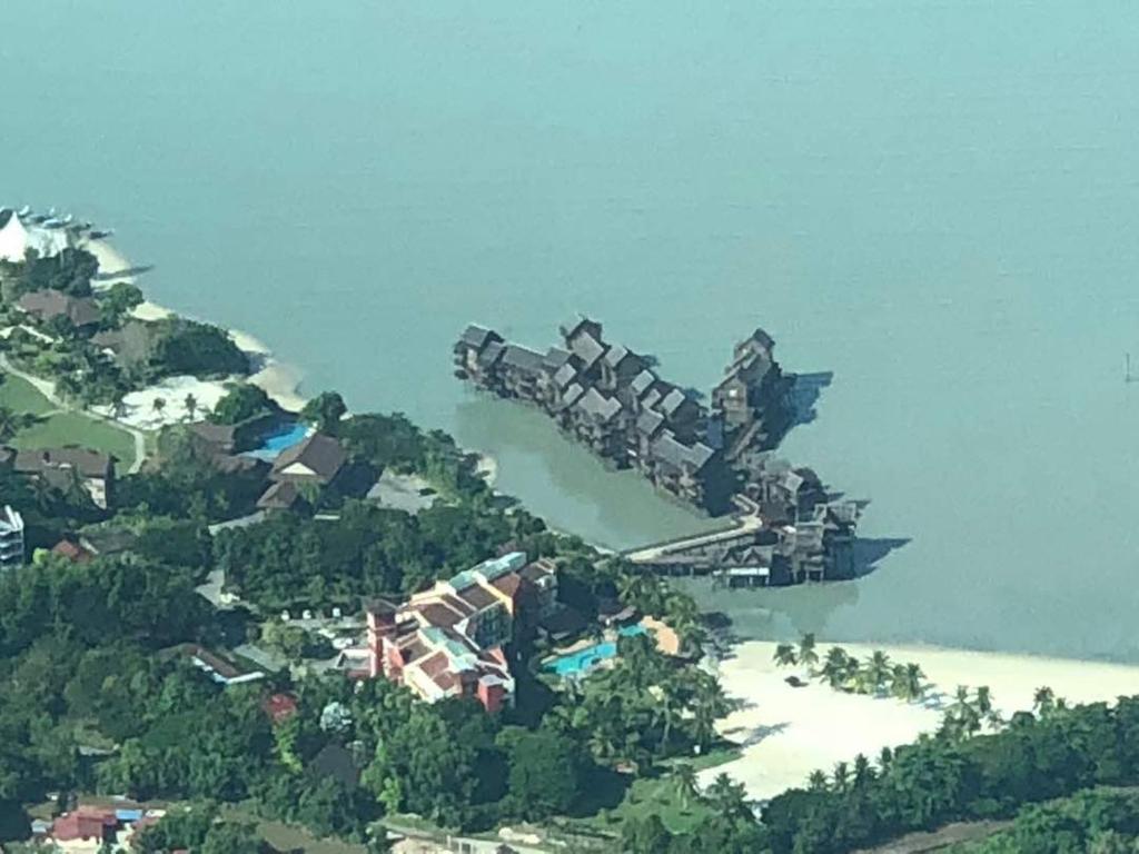 an airplane is flying over a small island at SEA VILLA LANGKAWI LAGOON in Pantai Cenang