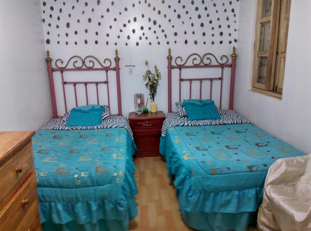 two beds sitting next to each other in a room at Escocie - Centro Historico in Quito