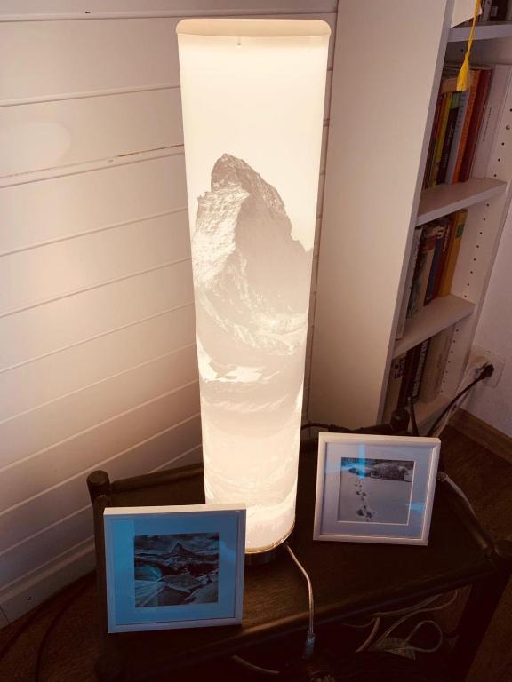 a large lamp on a table with two pictures at Chalet Memory in Zermatt