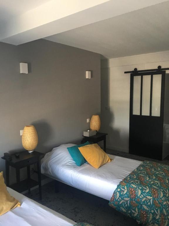 a bedroom with two beds and two lamps on the wall at Hôtel Le Mistral in Marseille