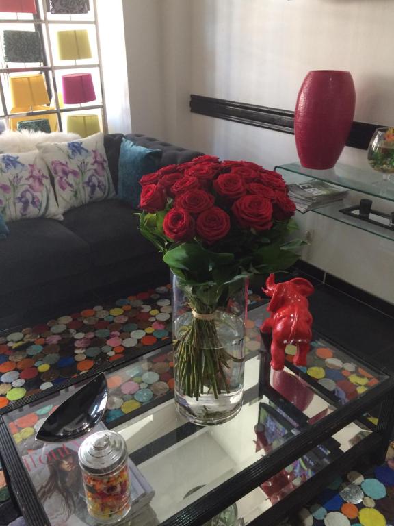 a vase with red roses on a glass table at Hôtel Le Mistral in Marseille