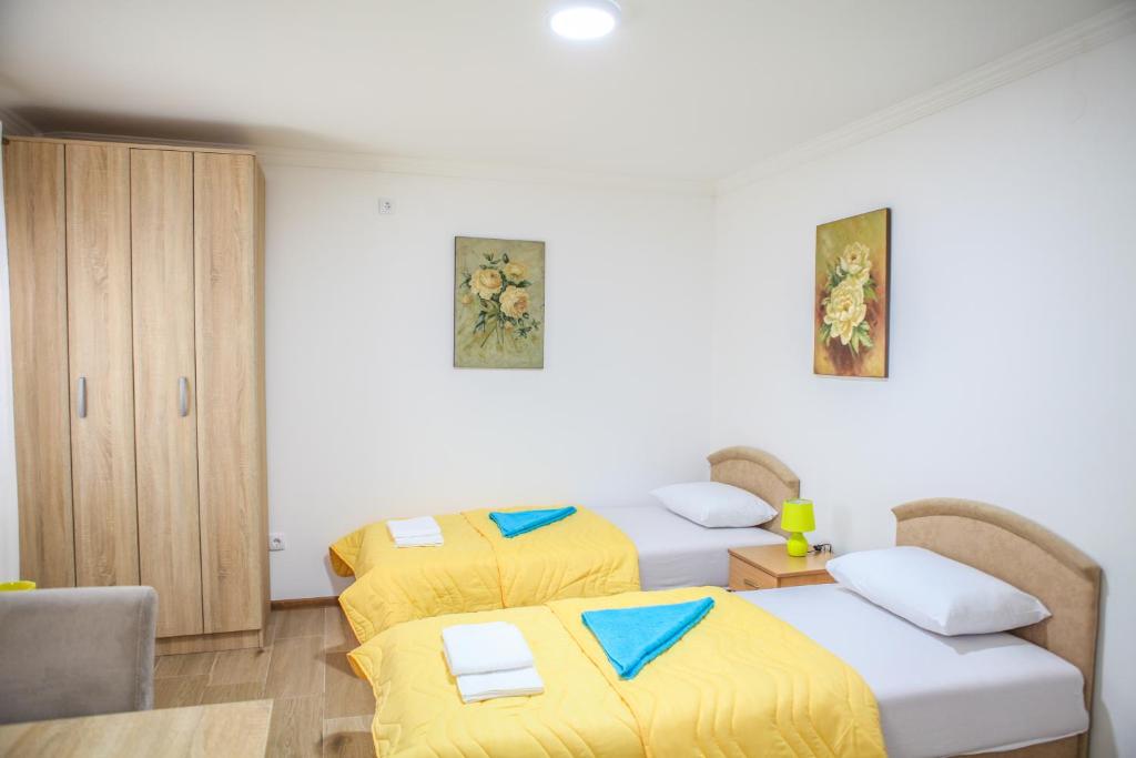 2 Betten in einem Zimmer mit gelber Bettwäsche in der Unterkunft Studio Kaća in Cetinje