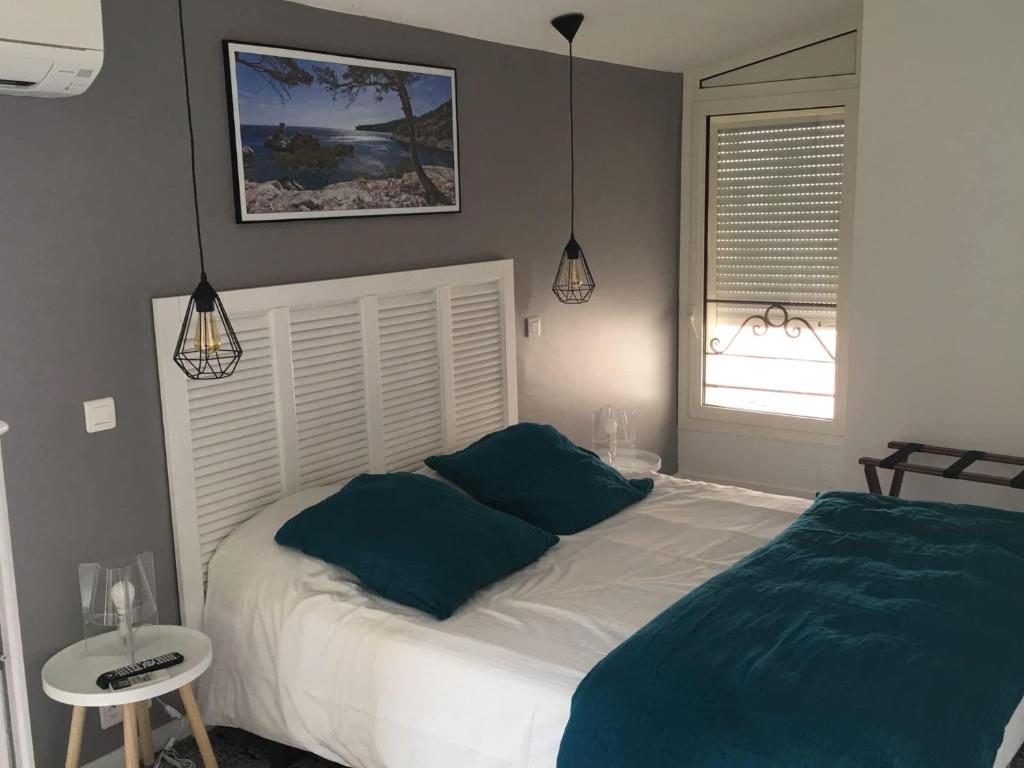 a bedroom with a white bed with blue pillows at Hôtel Le Mistral in Marseille