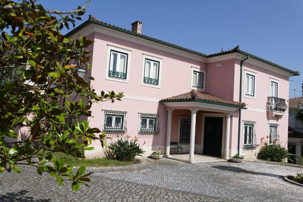 a pink house with a driveway in front of it at Casa Da Palmeira in Leiria