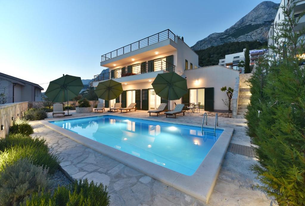una villa con piscina di fronte a una casa di Villa Dodo a Makarska