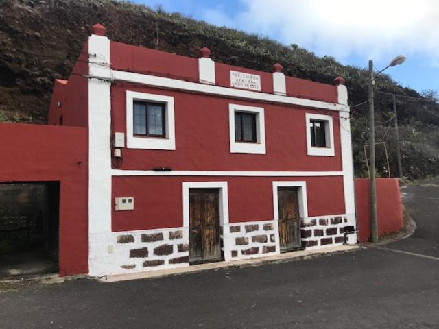 un edificio rojo y blanco al lado de una colina en Calle Montaña Aguarijo, en Mocanal