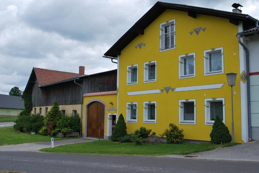 una casa amarilla con flechas pintadas a un lado. en Bauernhof Familie Tauber-Scheidl, en Grossmeinharts
