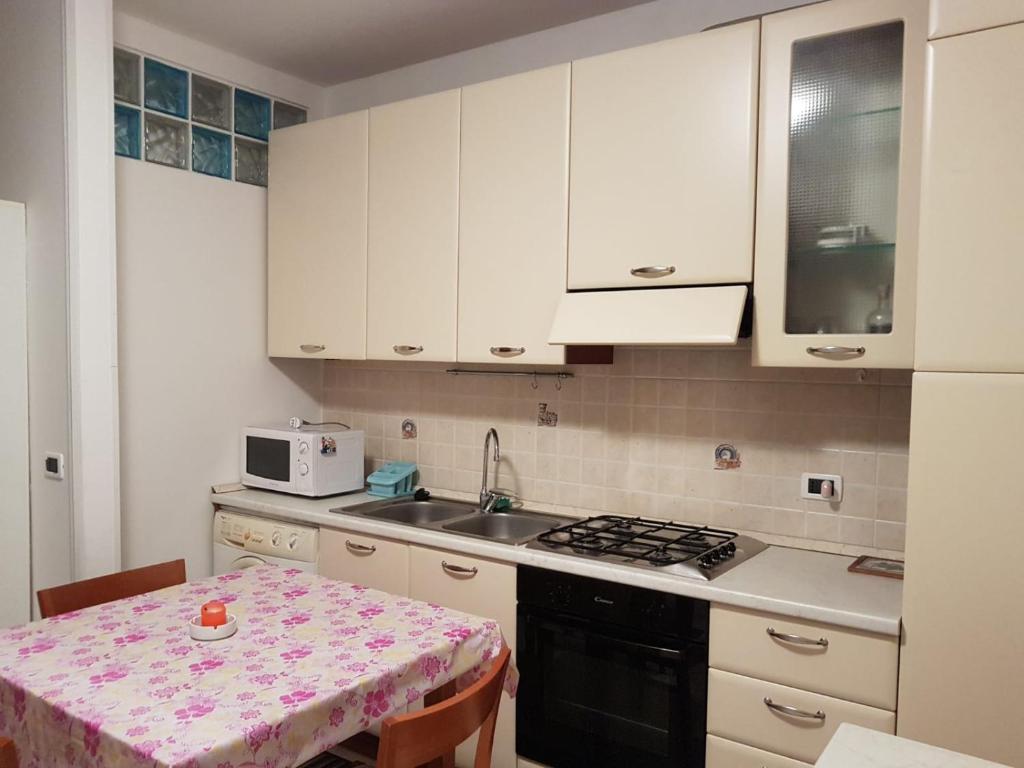a kitchen with white cabinets and a table and a sink at Appartamento Maestri in Sottomarina