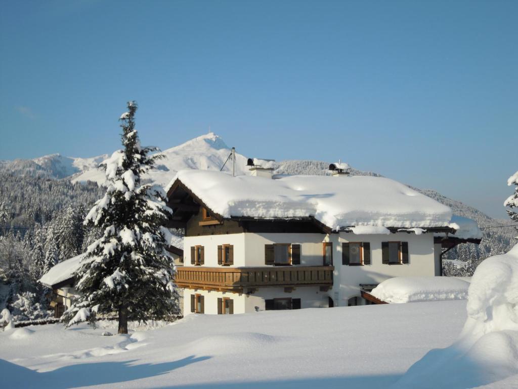 ein schneebedecktes Haus neben einem Baum in der Unterkunft Foidl Simon in Fieberbrunn