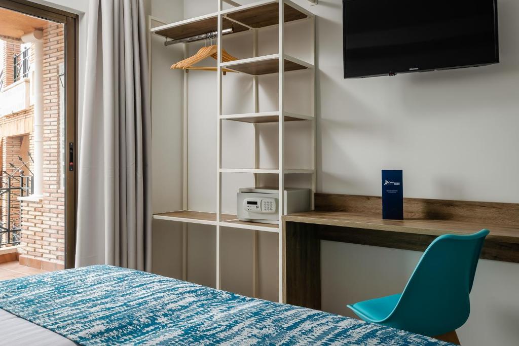 a room with a bed and a desk and a blue chair at Hotel Boutique Calas de Alicante in Alicante