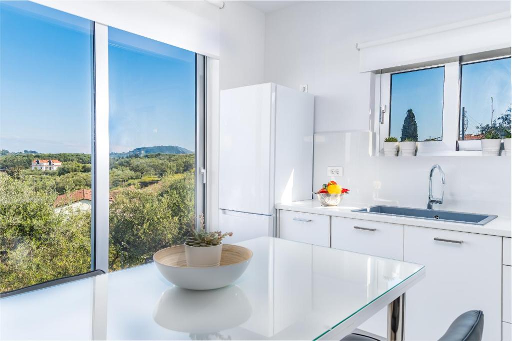 a kitchen with white cabinets and a large window at CasAlma II in Tsilivi