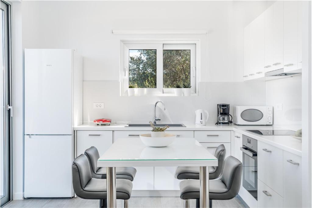 a white kitchen with a table and chairs at CasAlma II in Tsilivi