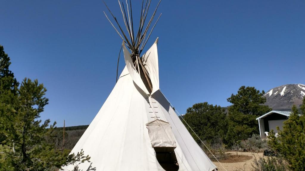 a white teepee with a mountain in the background at Tipi in Monticello