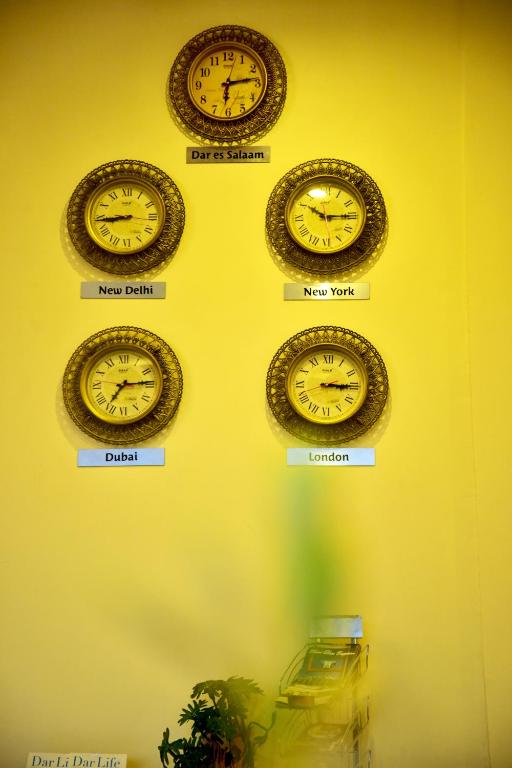 a row of clocks on a wall with different time zones at Hotel Blue Sapphire in Dar es Salaam