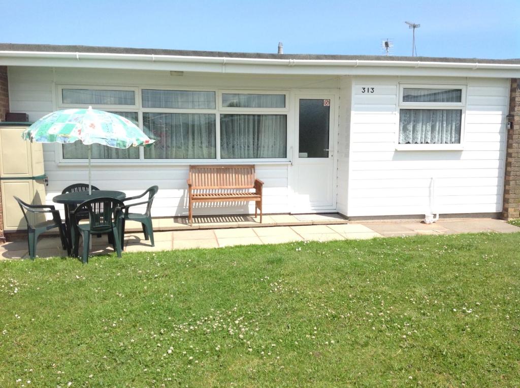 a table and chairs with an umbrella in front of a house at 313 Sundowner Holiday Park Hemsby in Hemsby