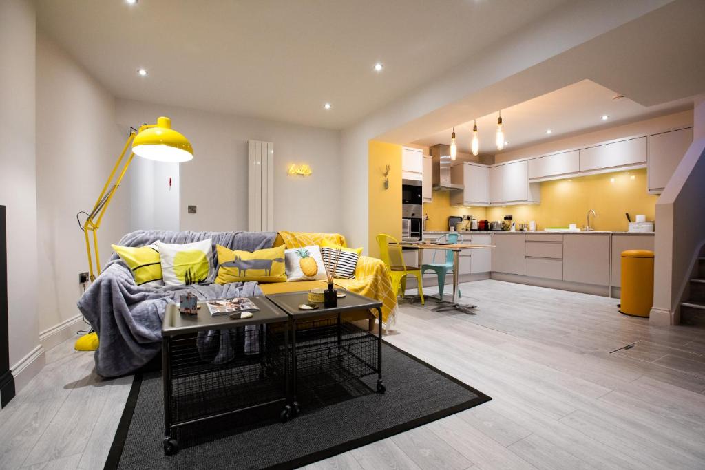 a living room with a yellow couch and a kitchen at Nadler House in Norwich