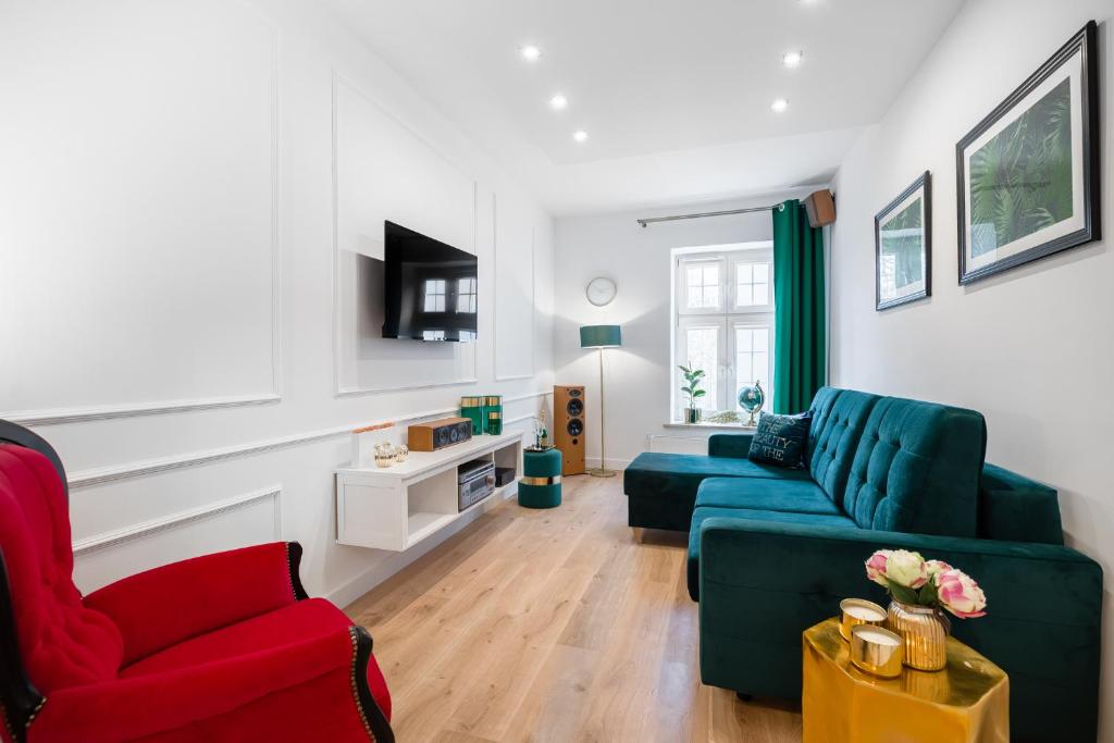 un soggiorno con divano verde e sedia rossa di Gedanum Apartment a Danzica
