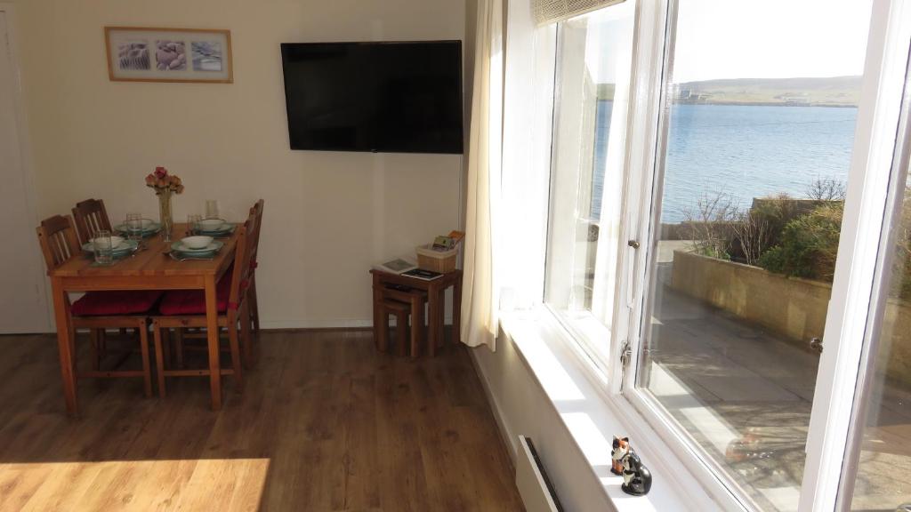 een eetkamer met een tafel en uitzicht op de oceaan bij Stouts Court Apartment in Lerwick