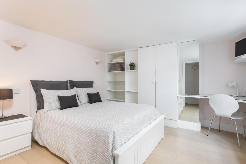 a white bedroom with a white bed and a desk at Excellent Apartment with Private PATIO, and PARK across the road in London