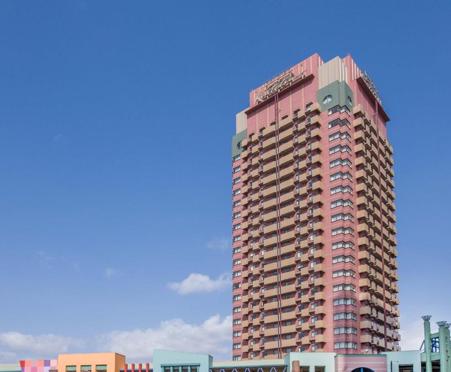 a tall pink apartment building on a city street at Hotel Kintetsu Universal City in Osaka