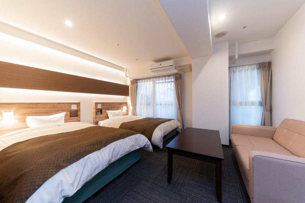 um quarto de hotel com duas camas e um sofá em HOTEL CITY INN WAKAYAMA Wakayama-Ekimae em Wakayama