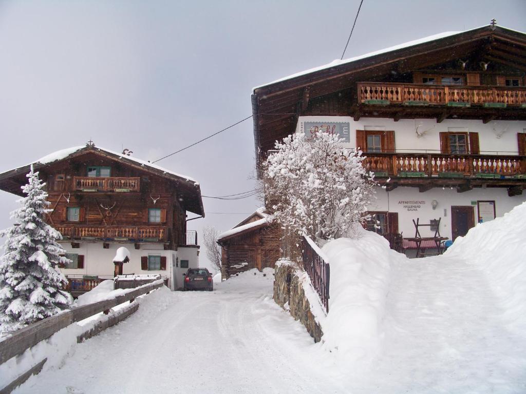 eine schneebedeckte Straße vor zwei Holzgebäuden in der Unterkunft Gästehaus Bichl in Umhausen