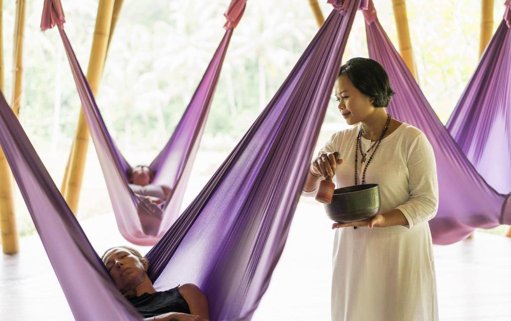 a woman standing next to two people in purple hammocks at Four Seasons Resort Bali at Sayan in Ubud