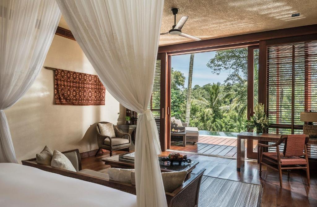a bedroom with a bed and a room with a large window at Four Seasons Resort Bali at Sayan in Ubud