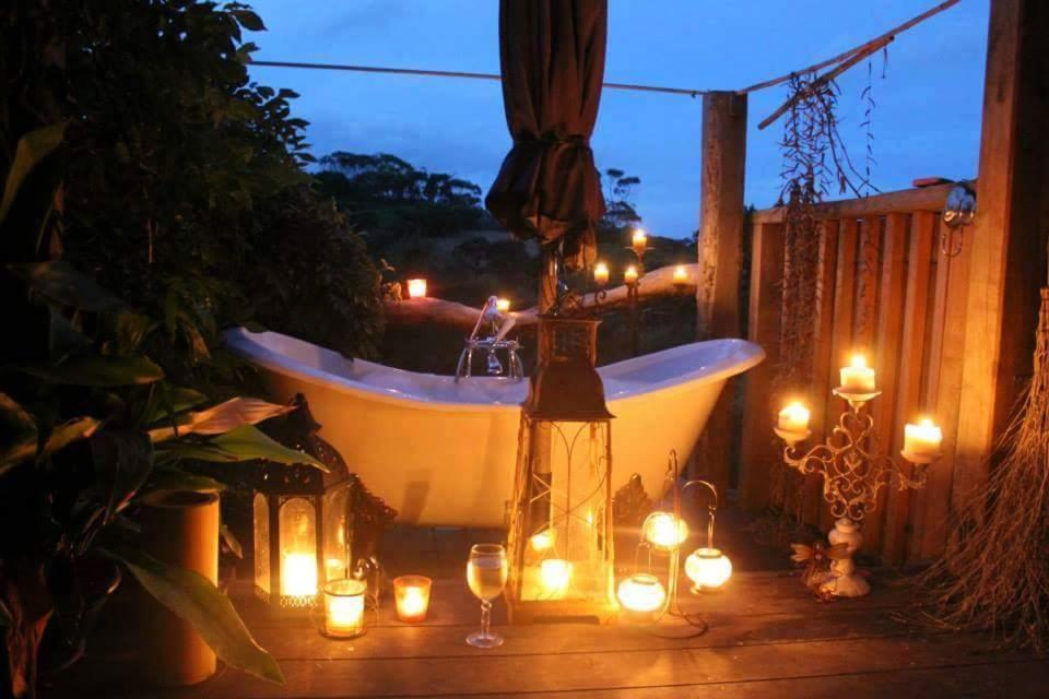 a bath tub with candles and a candle holder with lights at Freshwaterfarm Cottages - Muriwai in Waimauku