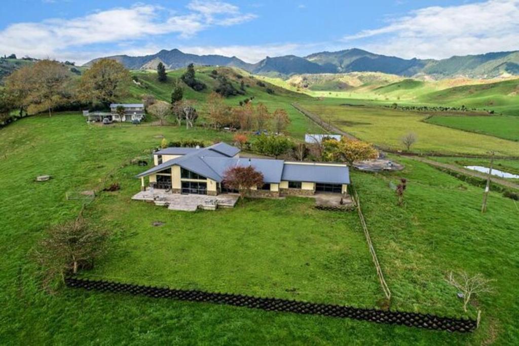 an aerial view of a house on a green field at Waiotahe Dairy Farm Hideout in Waiotahi