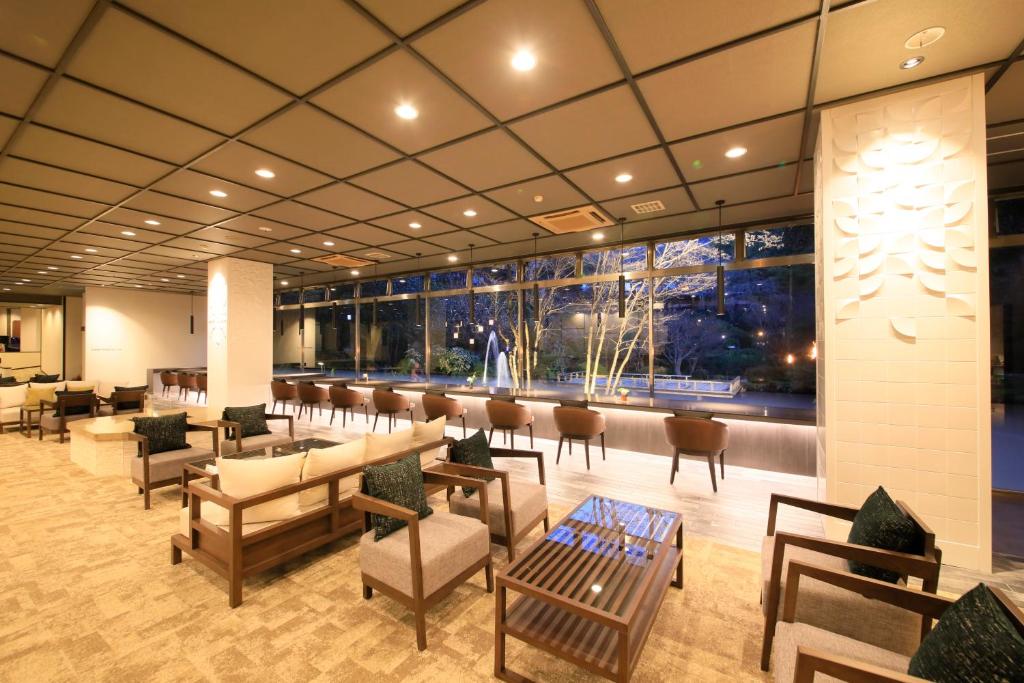 a lobby with a waiting area with tables and chairs at Hotel Kamogawaso in Takekara