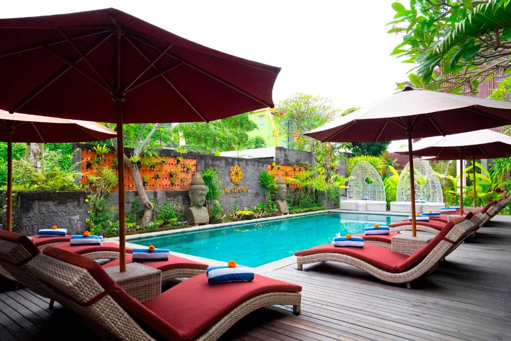 een rij stoelen met parasols naast een zwembad bij Freddies Villas Ubud Bali in Ubud