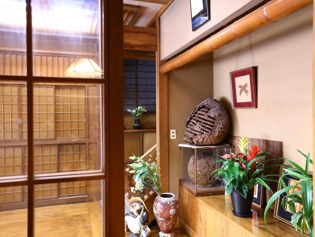 a room with a window and plants on a shelf at Ikariya Ryokan in Yamanouchi