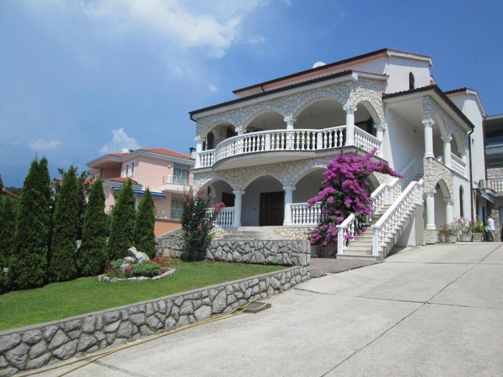 a large white house with a balcony and purple flowers at Apartments Villa Sandra in Opatija