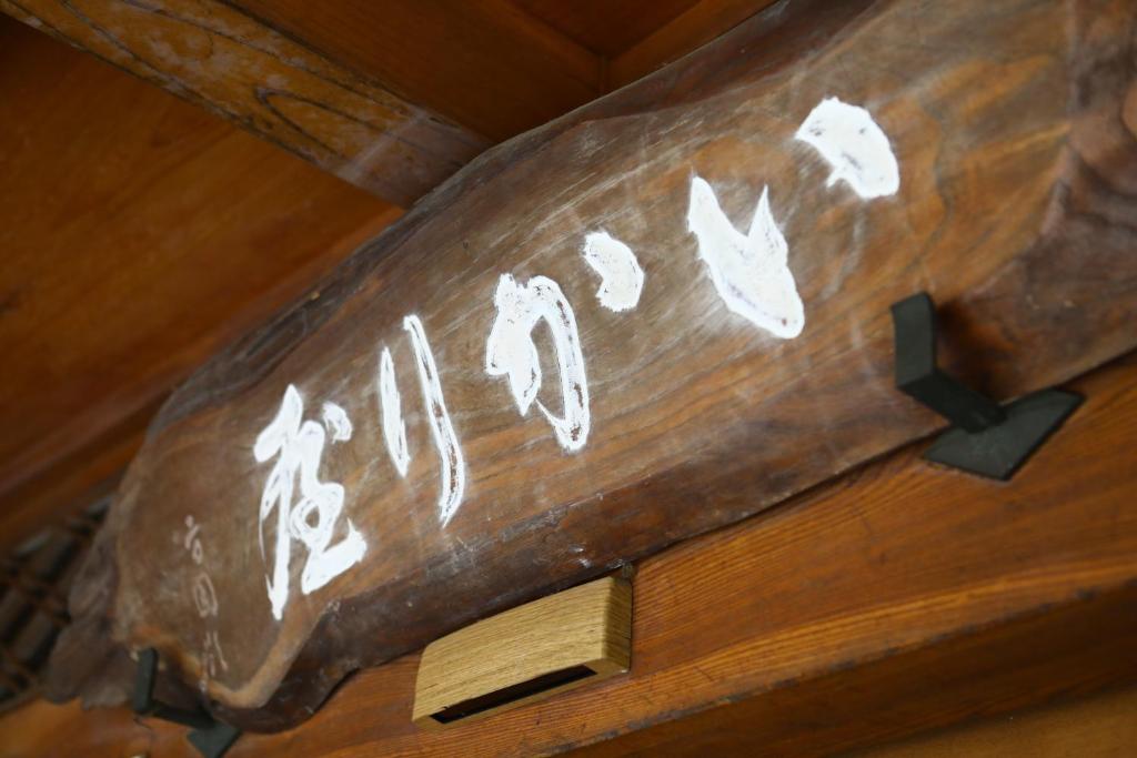 a sign on a wooden table with writing on it at Ikariya Ryokan in Yamanouchi