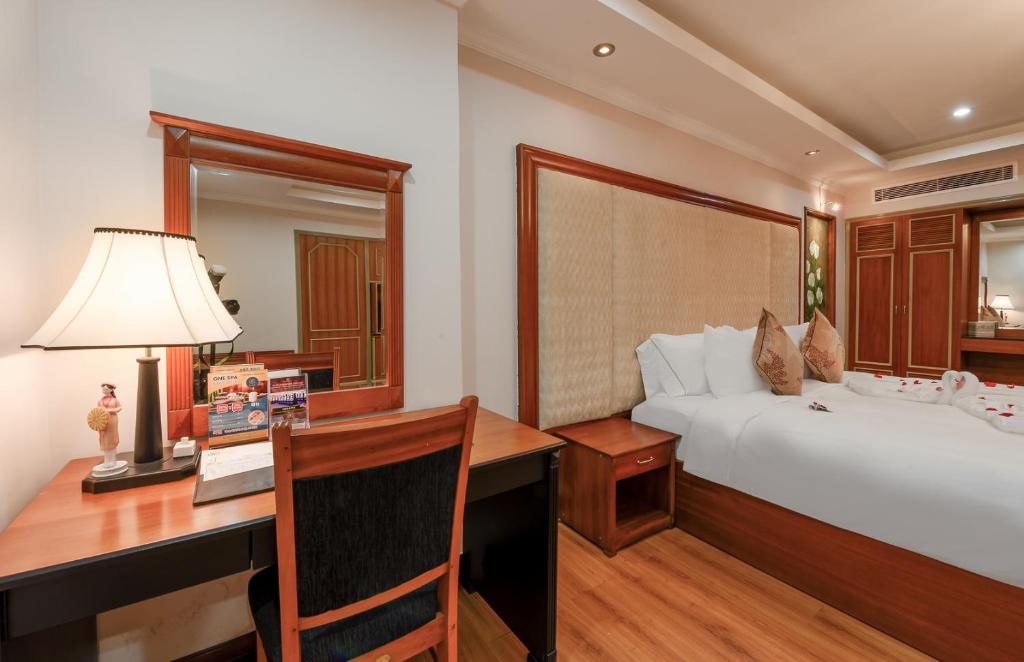 A bedroom corner with a narrow writing desk, lamp and upholstered bed.